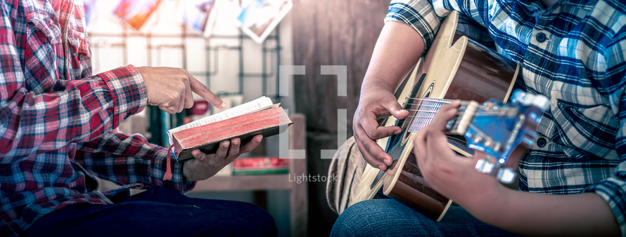 hands of young christians share a bible and sing with a guitar to worship God, Christian worship