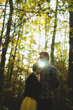 a couple standing together in a forest 