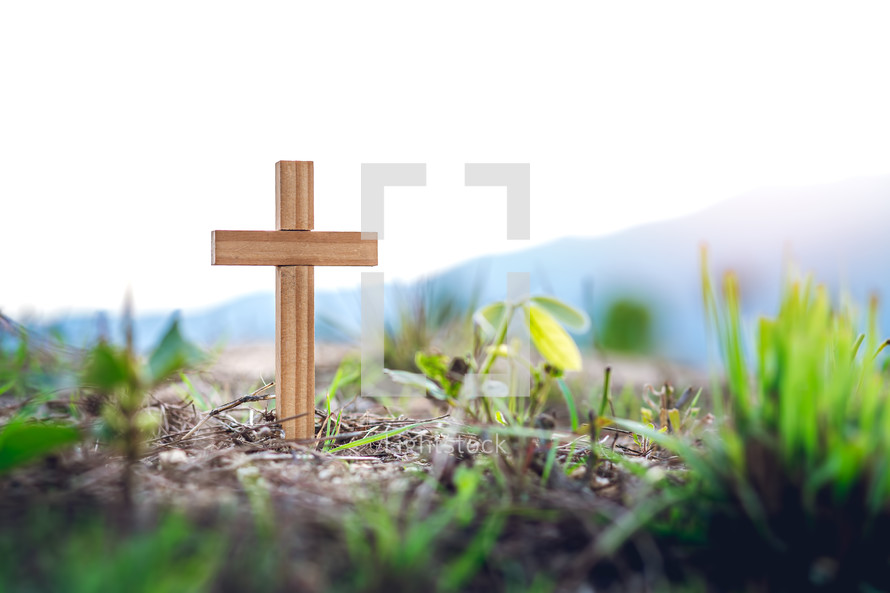 cross in the ground with mountains in background 