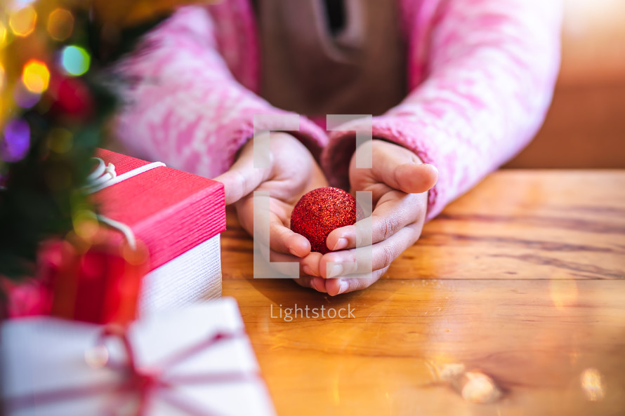 little girl holding a Christmas ornament in cupped hands 