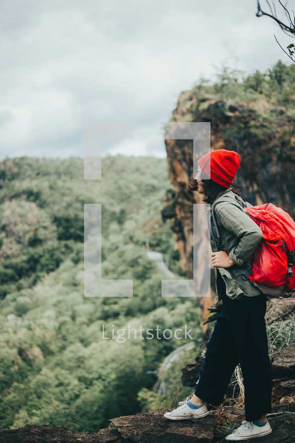 a woman backpacking through a forest 