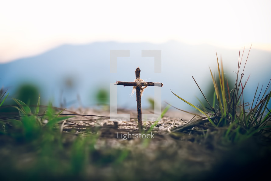 cross in the ground with mountains in the background 