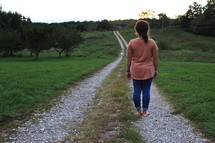 a woman standing on a gravel road 