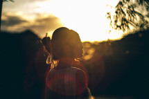 a young woman standing in sunlight at sunset 