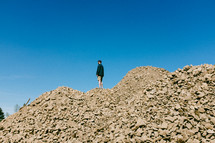 a man standing at the top of a rock pile 