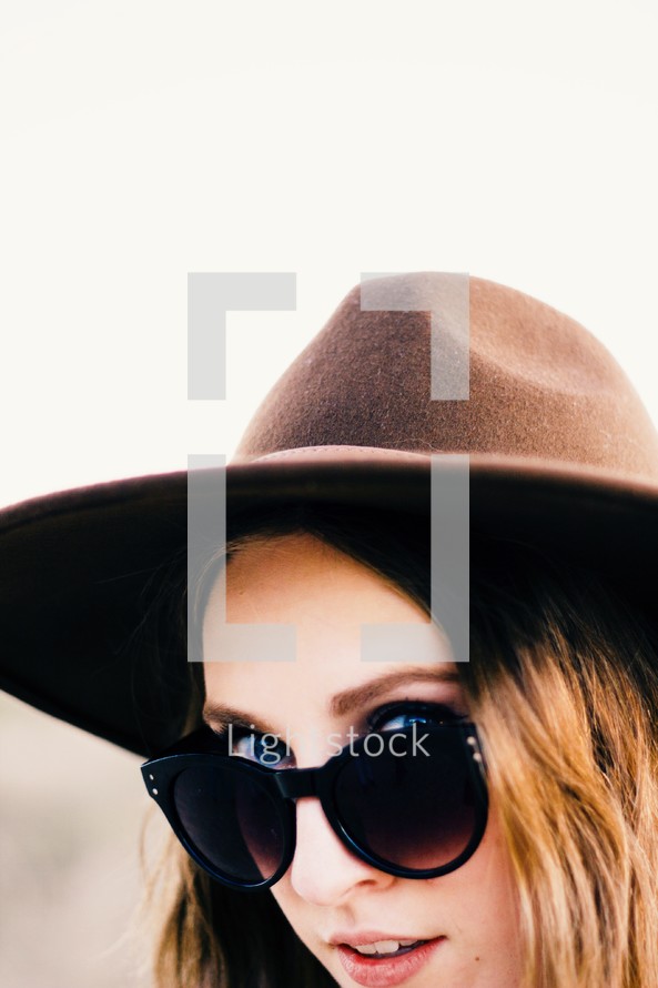 a woman peeking from behind sunglasses 