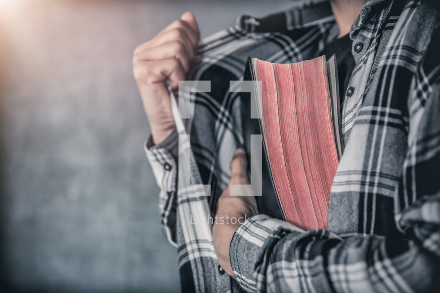 a teen hiding a Bible in his shirt 