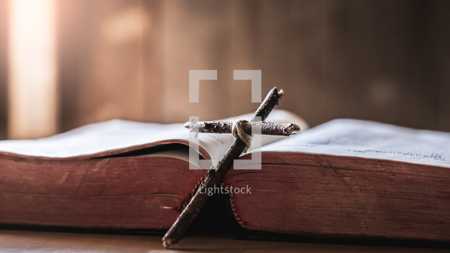 cross made of sticks laying against an open Bible 