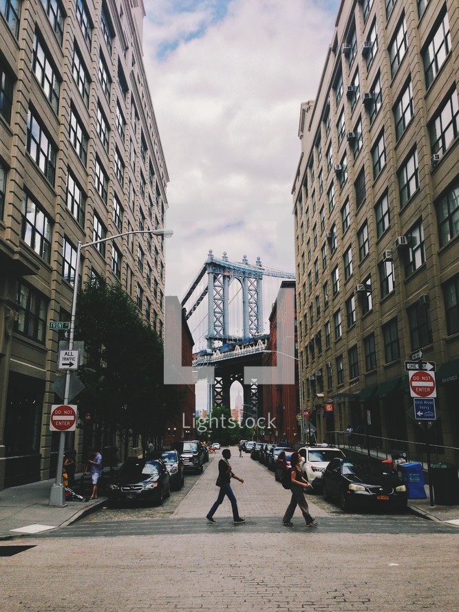 A crosswalk and a view of the Brooklyn Bridge. 