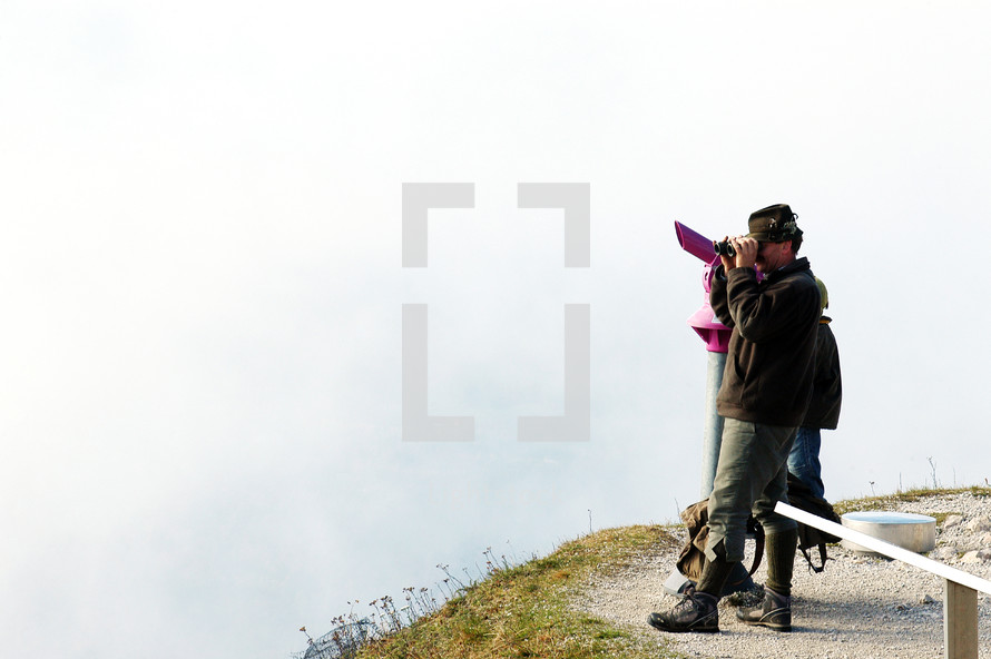 man with binoculars on a mountain top 