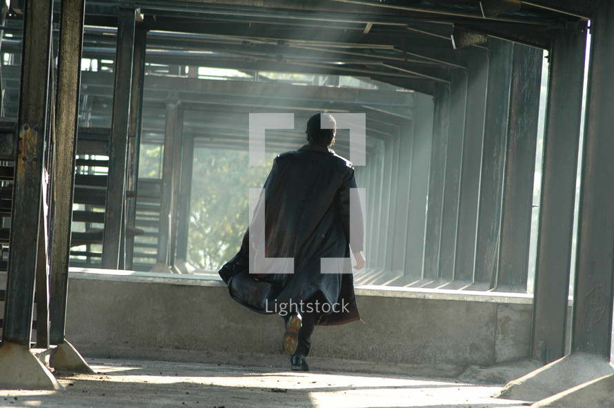 man in a trench coat walking through an abandoned building 