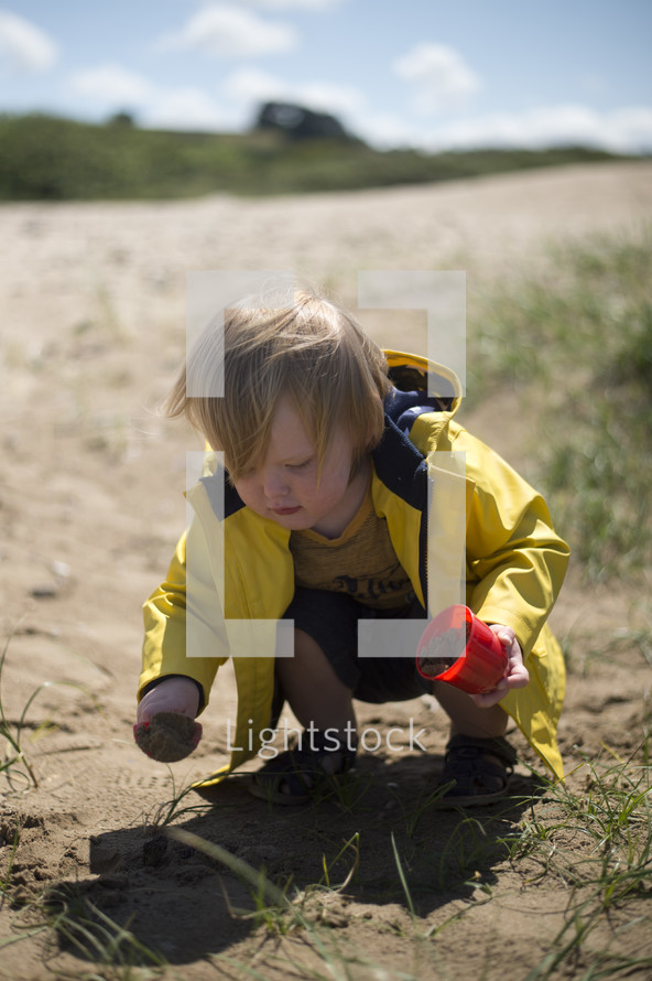 a toddler boy digging in dirt 