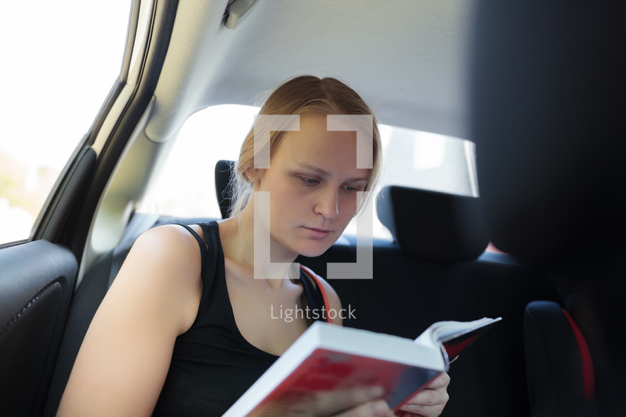Woman reading a book in the car