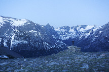 a man standing and looking out at snow capped mountains peaks 
