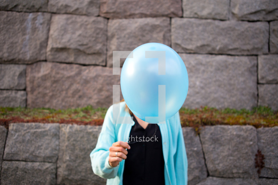 a woman holding a balloon in front of her face 