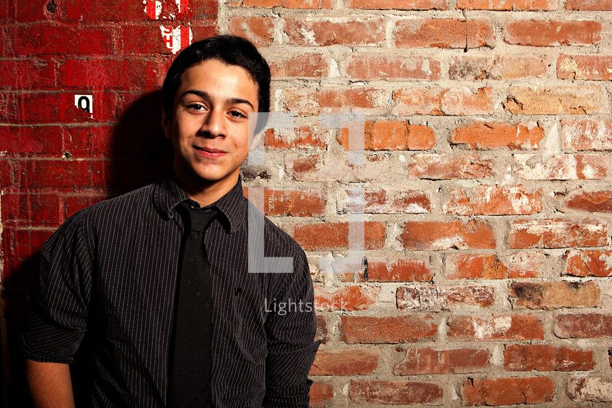 teen standing in front of a brick wall