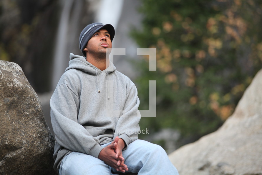 man sitting on a rock in prayer