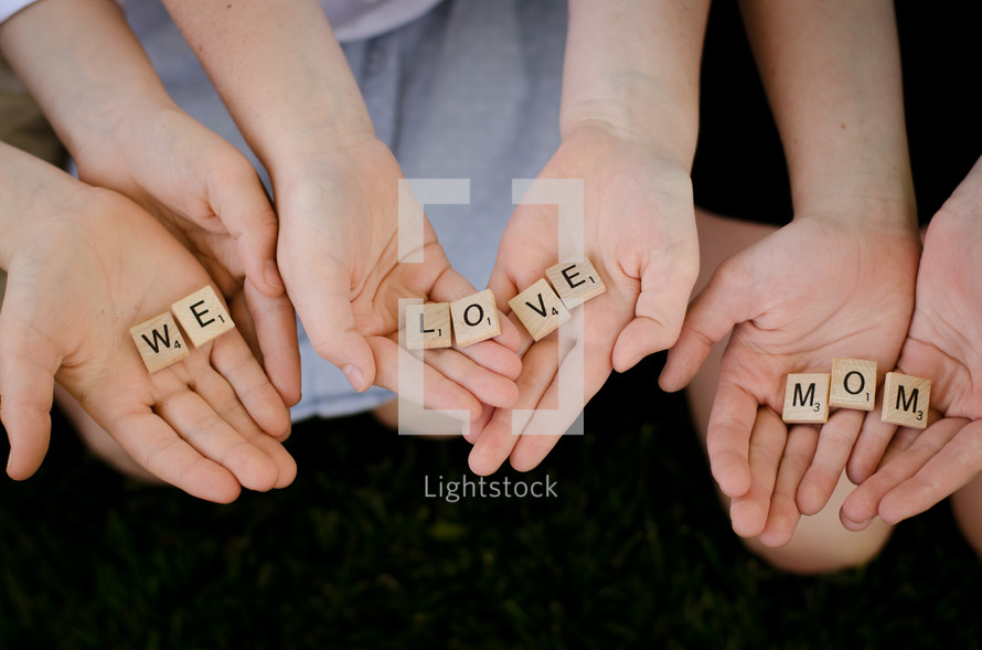 children holding scrabble pieces that read we love mom 