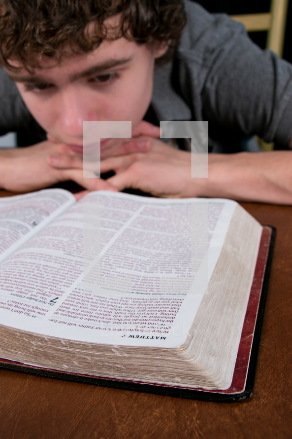 A teen boy reading a Bible. 