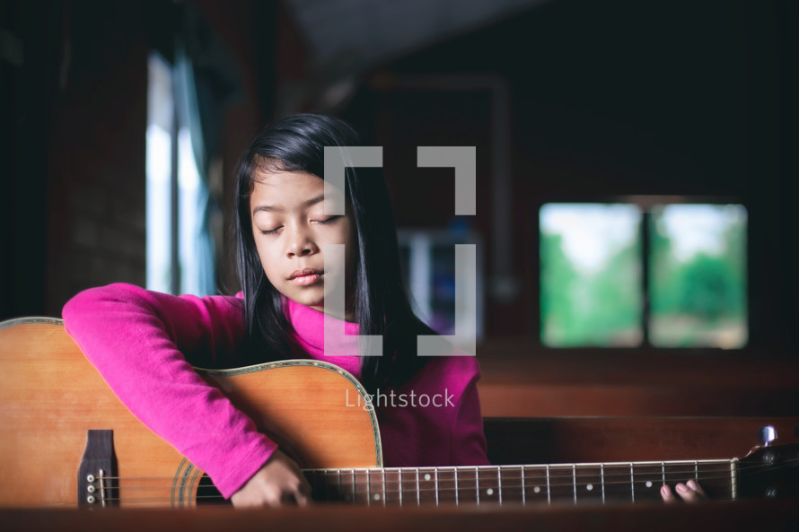 a girl child playing a guitar 