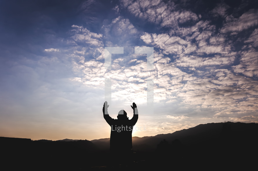 silhouette of raised hands at sunset 