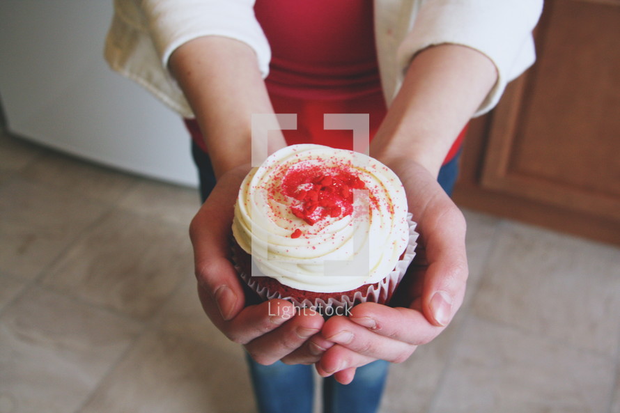 A woman holding out a cupcake.