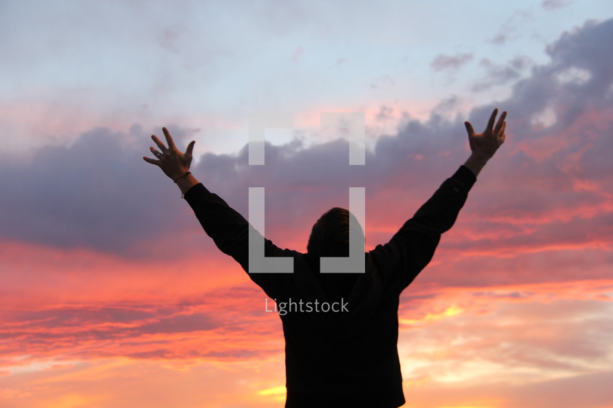man with his arms raised praising God
