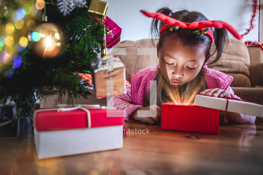 toddler girl with gifts under a Christmas tree 
