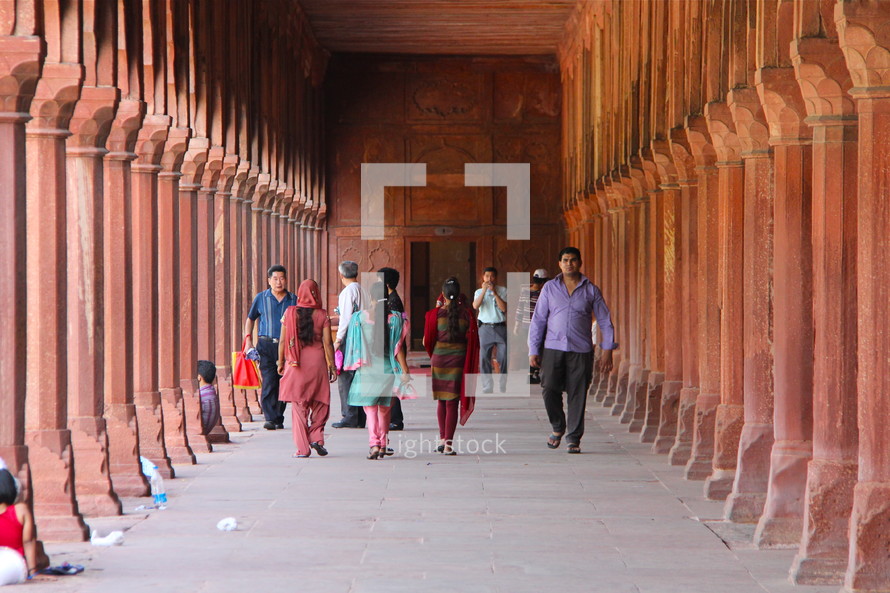 People walking through the covered walkway surrounding the Taj Mahal