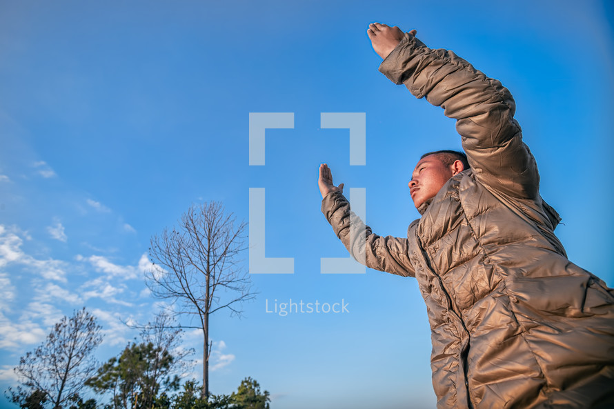 a man in a coat with hands raised 