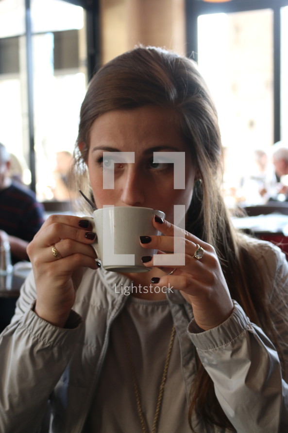 a woman sipping from a mug 