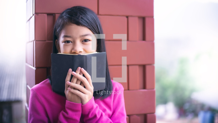 a shy child holding a Bible 