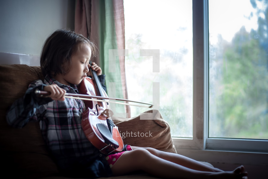 a girl playing a violin in a window 