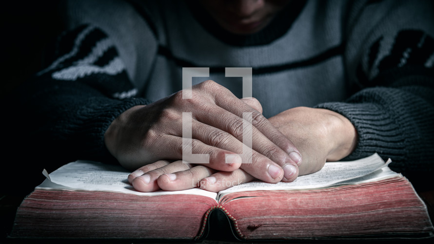 hands on a Bible in prayer 