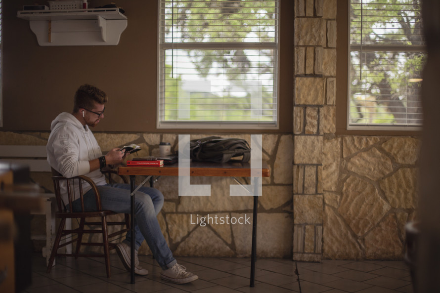 a male sitting at a table reading a Bible 