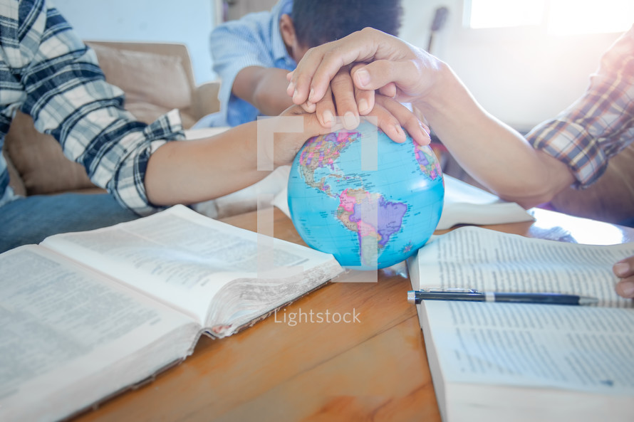 praying hands on a globe at a small group Bible study 