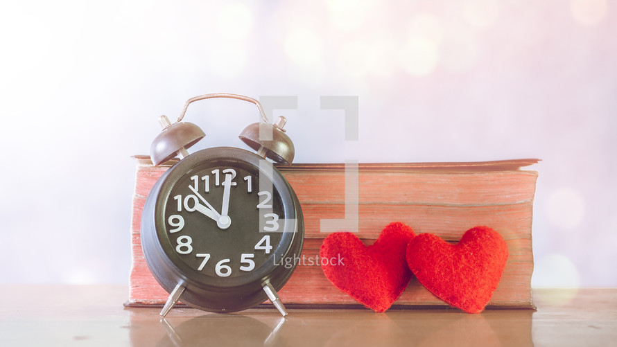 Alarm clock, red hearts, and Bible 