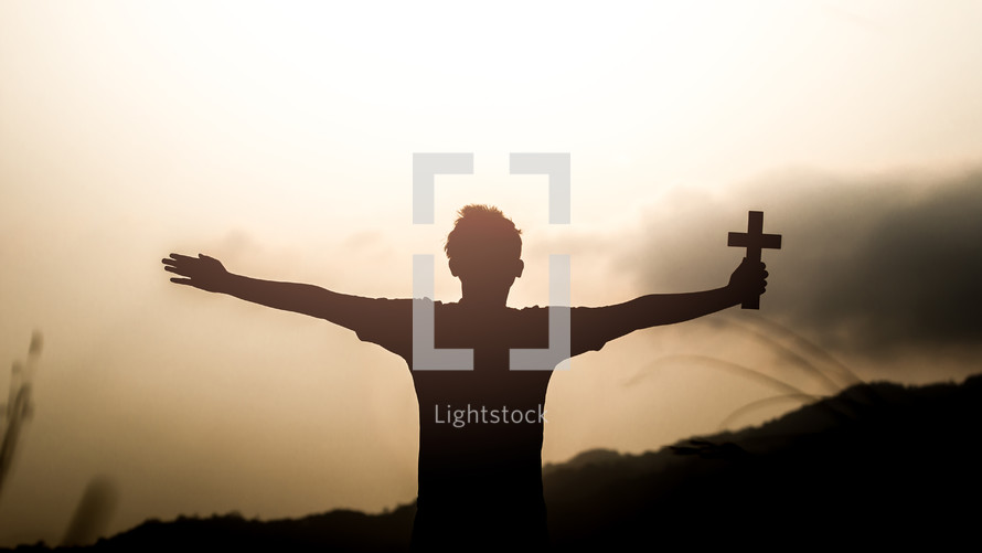 a boy with outstretched arms holding a cross 