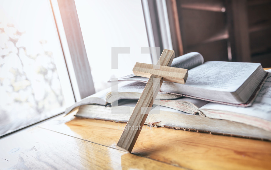 wooden cross in front of an open Bible