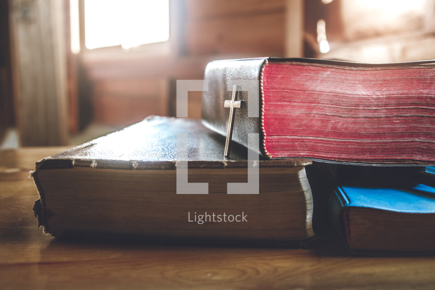 several closed Bibles on a wood table 