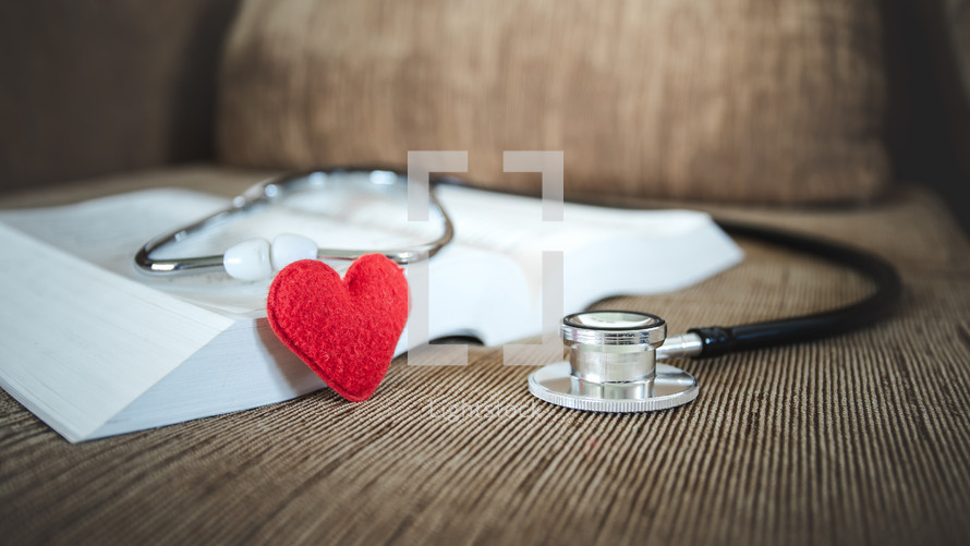 small felt heart and stethoscope on an open Bible 
