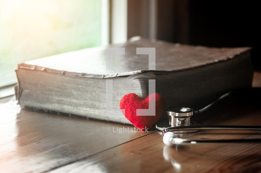 stethoscope on a Bible and small red heart 