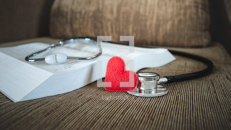 small felt heart and stethoscope on an open Bible 