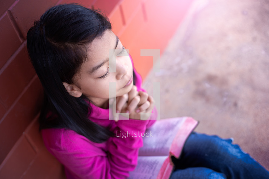 a girl reading a Bible outdoors 