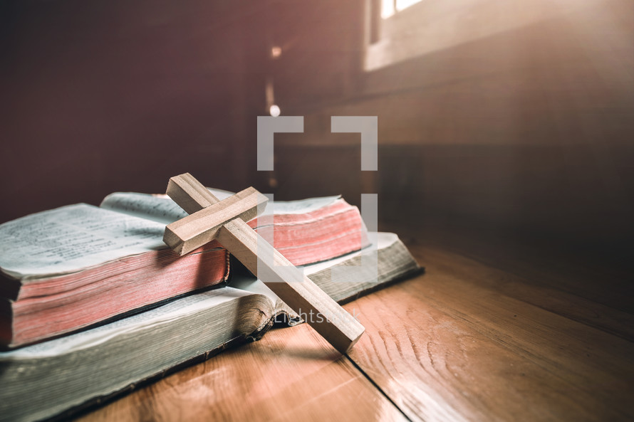 wooden cross leaning against an open Bible 