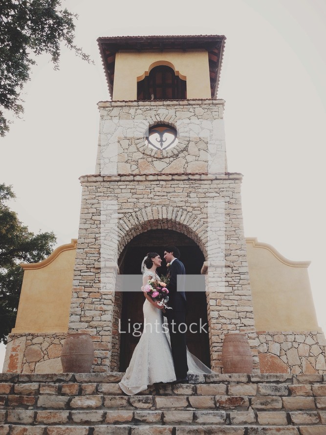 bride and groom kissing in front of a church 