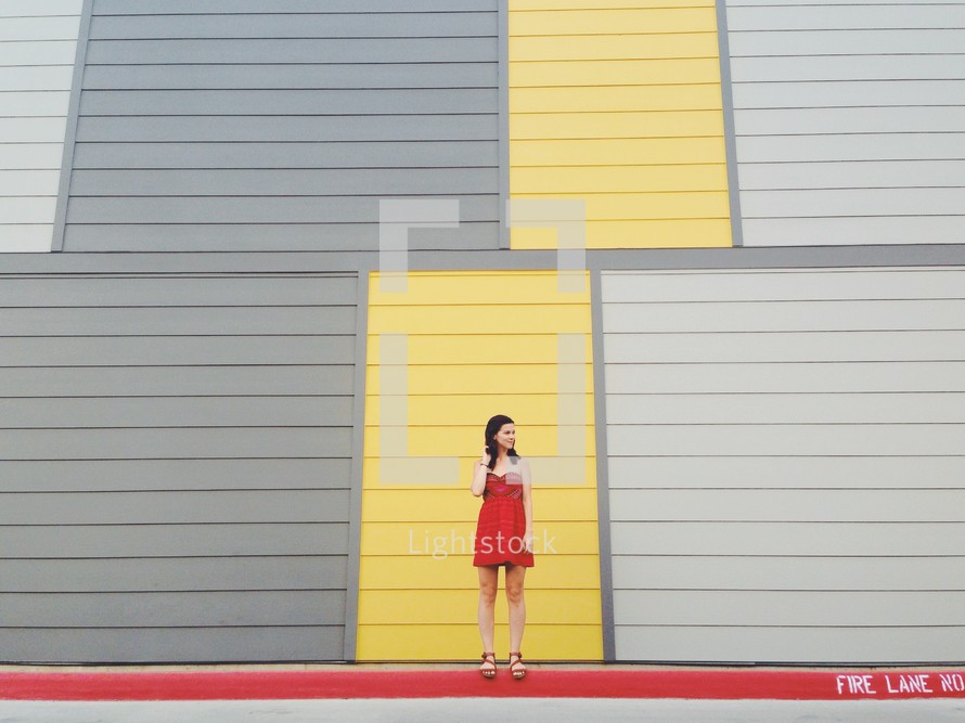 woman in a red dress standing in front of a yellow and gray wall 