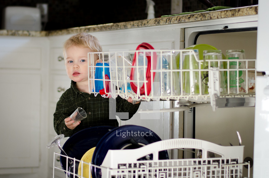 a toddler boy loading a dishwasher 
