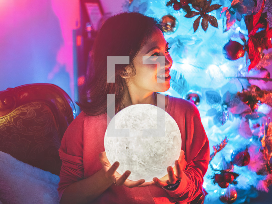 a smiling woman holding a glowing moon 