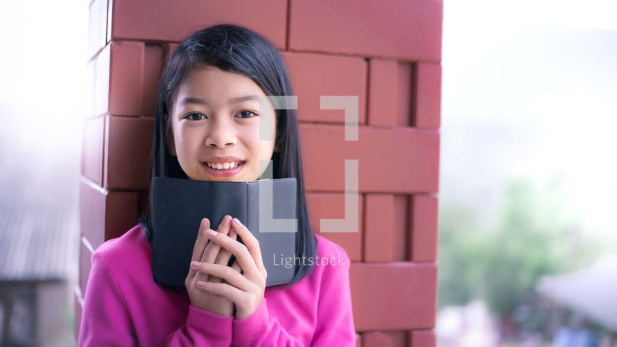 a smiling child holding a Bible 